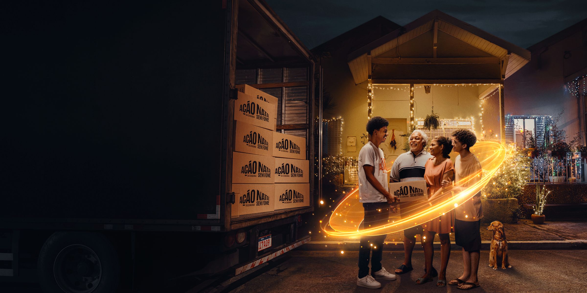 Família sorrindo em frente de casa, na noite de Natal, recebendo uma caixa da Ação da Cidadania, envolvida por um rastro de luz dourada.